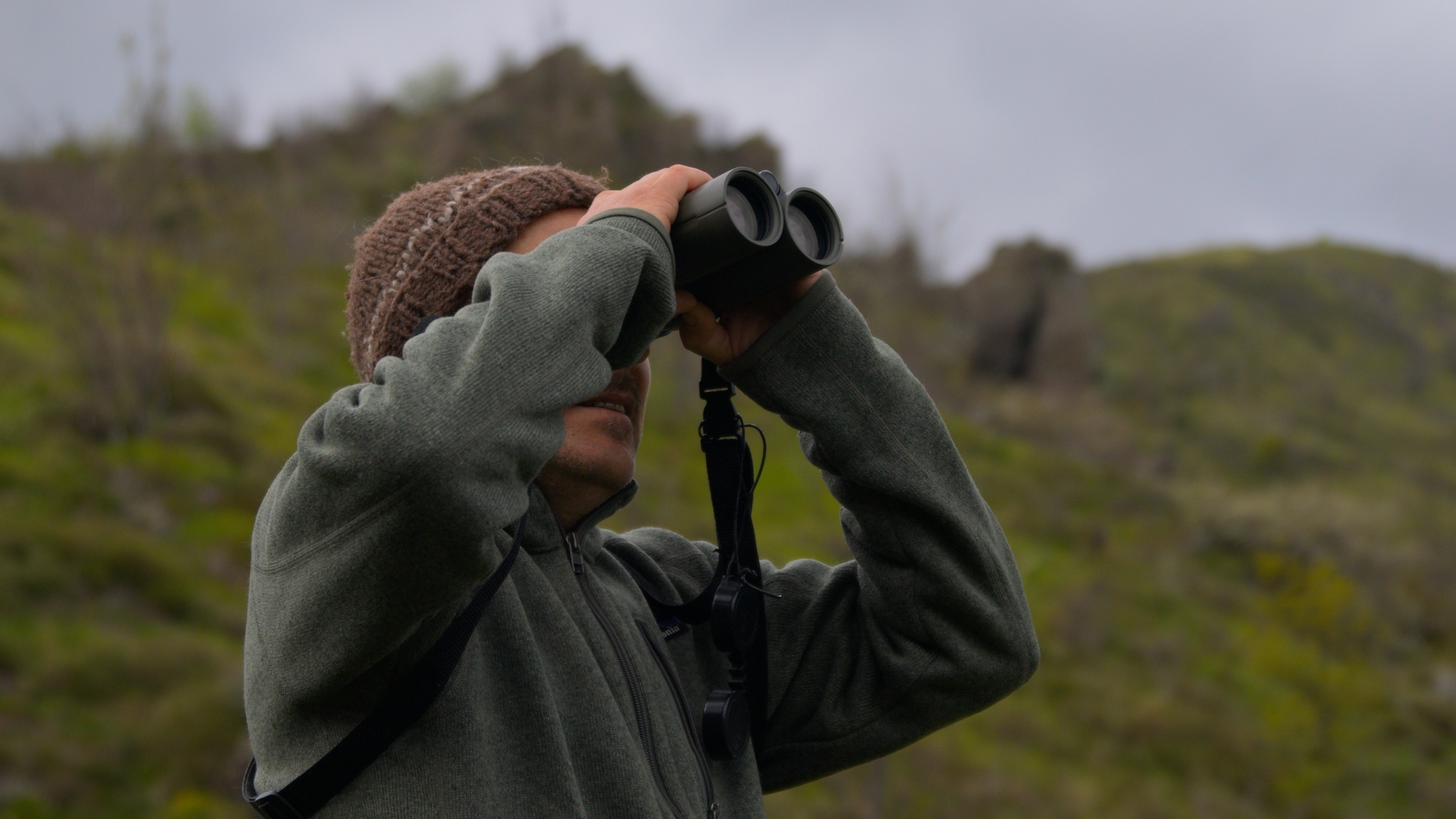 Operatore con il binocolo osserva il territorio dell'Appennino durante una ripresa documentaria